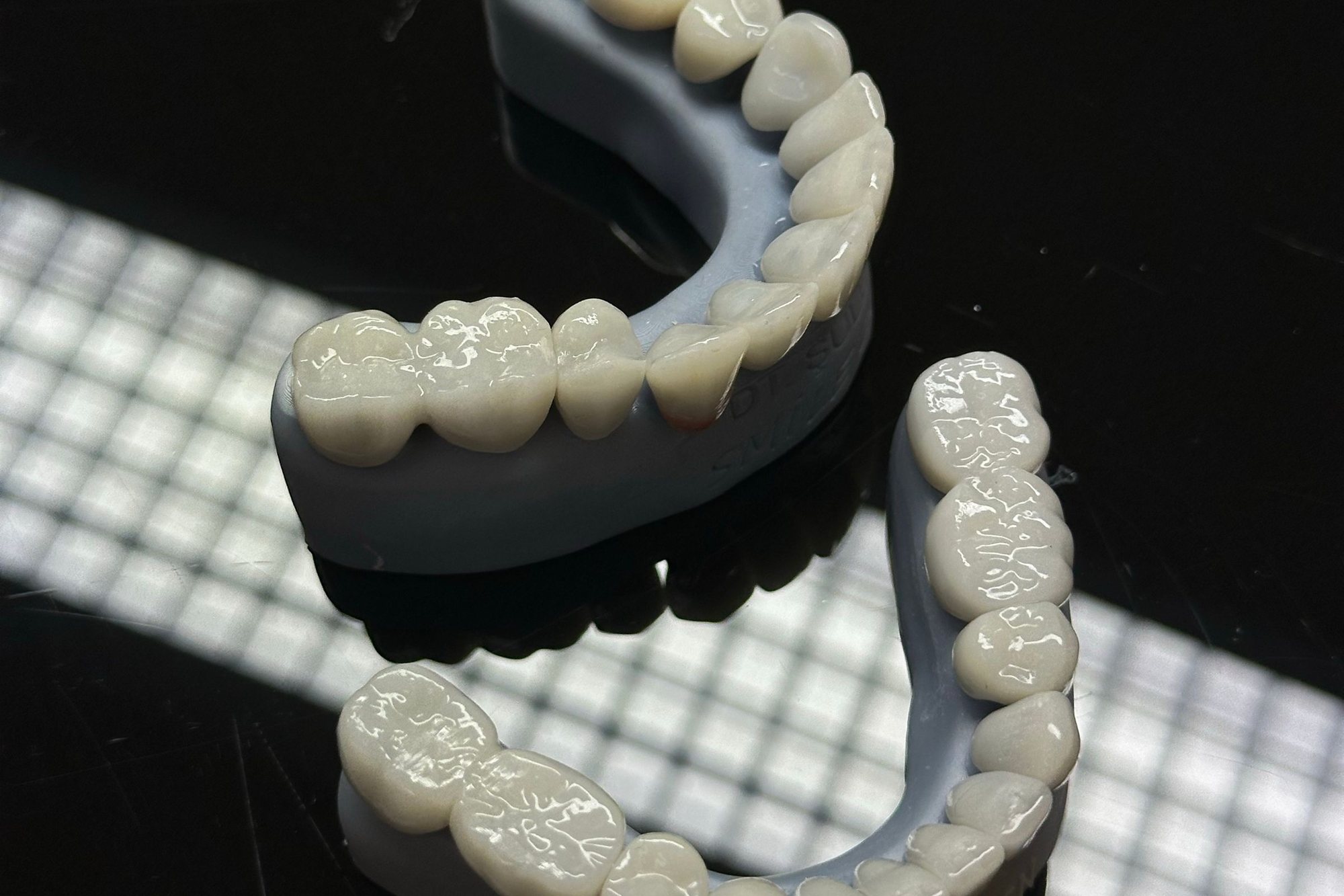 Lucrări dentare pentru arcada superioară și inferioară, așezate pe o masă luminată de laborator