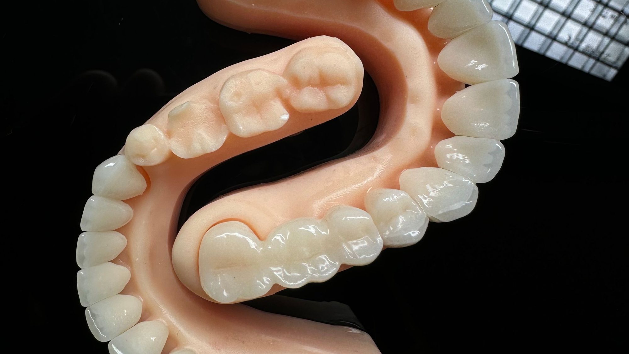 Lucrare dentară pe toată arcada, cu dinți și gingie artificială, pe o masă de laborator luminată