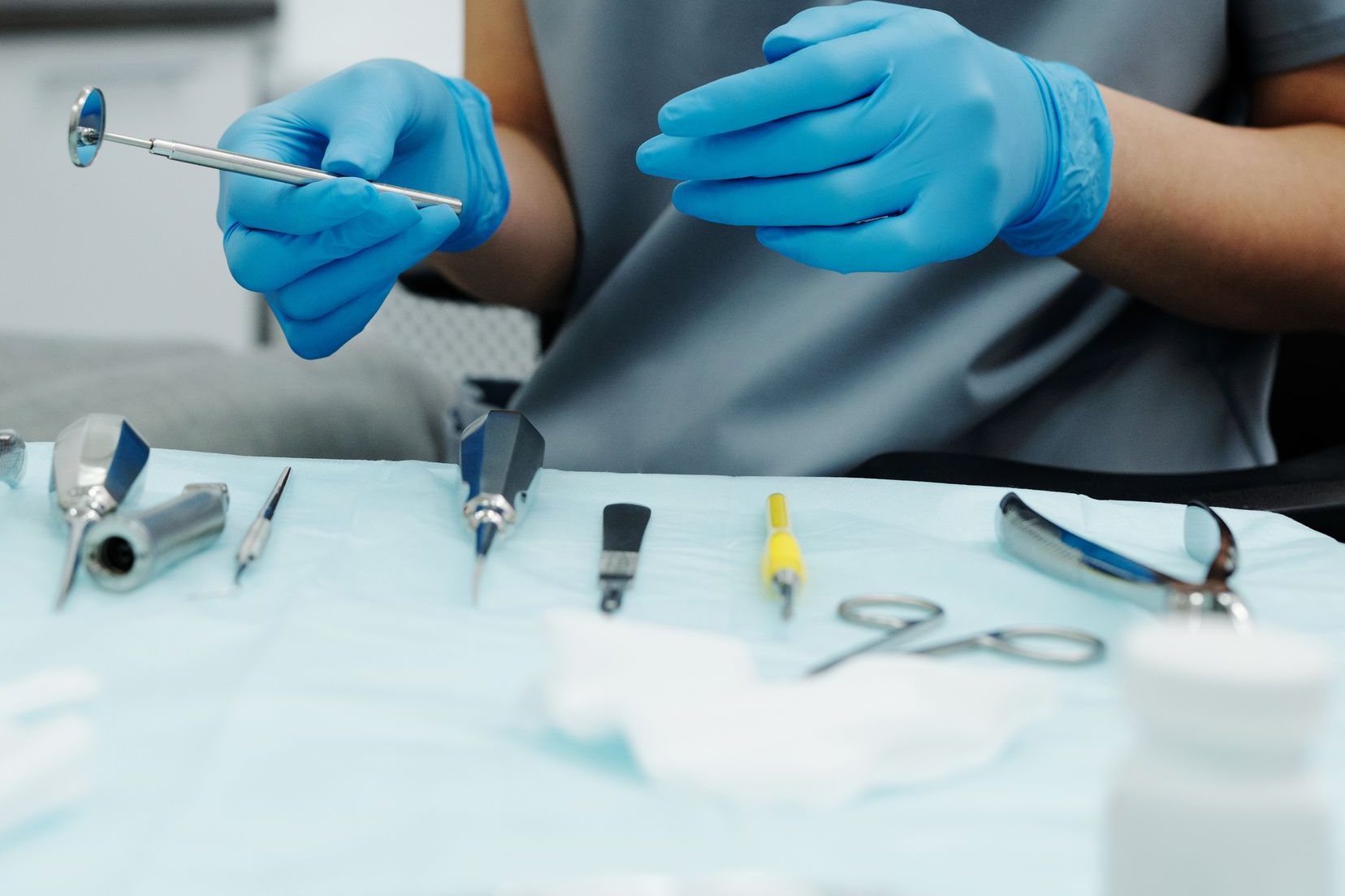 Mâini cu mănuși deasupra unei mese cu instrumente chirurgicale stomatologice sterile